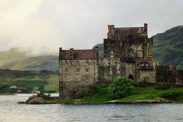 A stone castle on the water's edge under an overcast sky