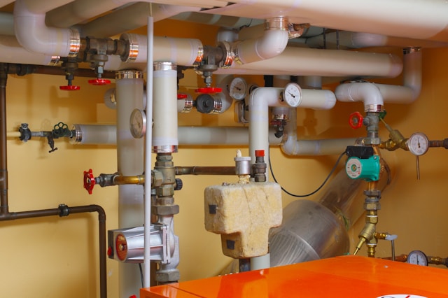 A wall of heating pipework, valves and gauges in a boiler room