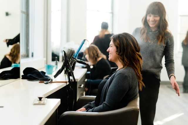 A stylist chatting with a seated client at a mirror station