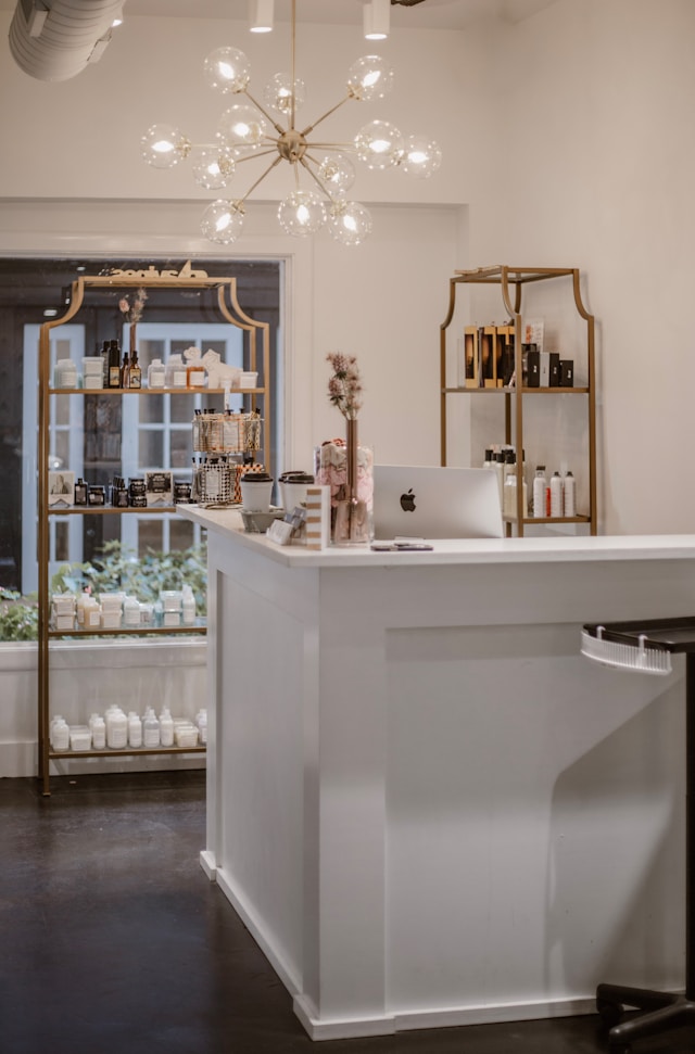 A brass shelving unit stocked with retail products beneath a chandelier