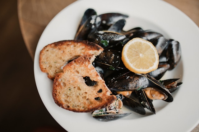 A plate of smoked mussels with lemon and toasted bread