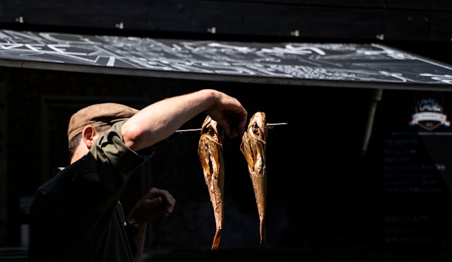 Isla Guthrie lifting smoked fish from the rods outside the kiln
